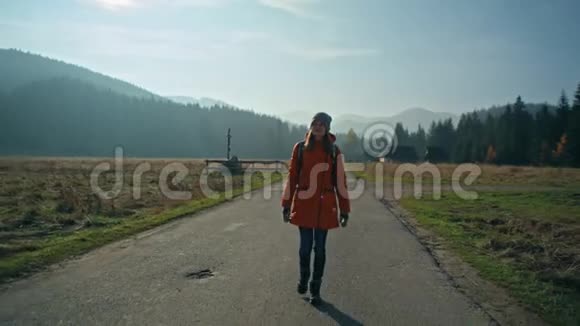 带背包的女孩正走在阳光明媚的秋天乡村的路上视频的预览图