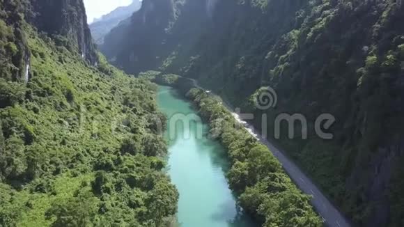 空中蓝色河流和峡谷中蜿蜒的河岸公路视频的预览图