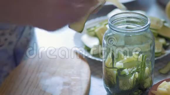 特写镜头一个老女人的手轻轻地叠在一个玻璃罐里包在黄瓜片白胡椒里视频的预览图