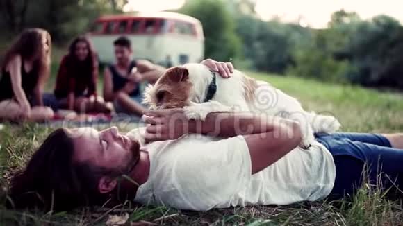 一群年轻的朋友带着一只狗坐在草地上穿过乡村视频的预览图