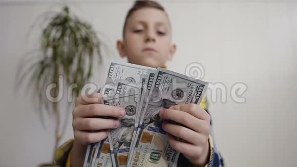 男孩计数许多美国100张钞票的观点小男孩数美国货币白色背景室内视频的预览图