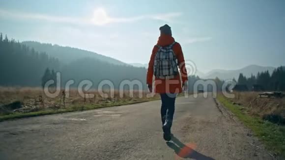 背着背包的女孩在阳光明媚的山间公路上视频的预览图