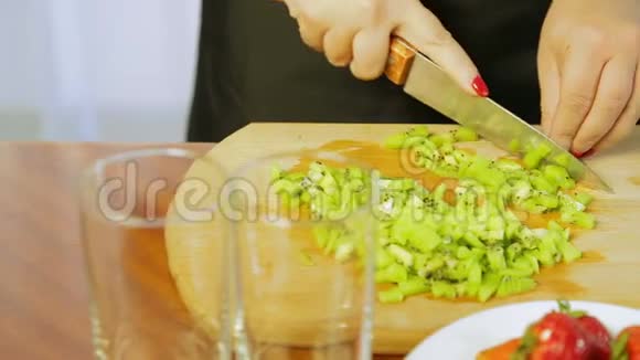 女人把成熟的猕猴桃切成薄片用一把刀放在木板上视频的预览图
