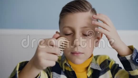 孩子正在用木梳梳理头发看着镜头一个蓝眼睛男孩的肖像视频的预览图