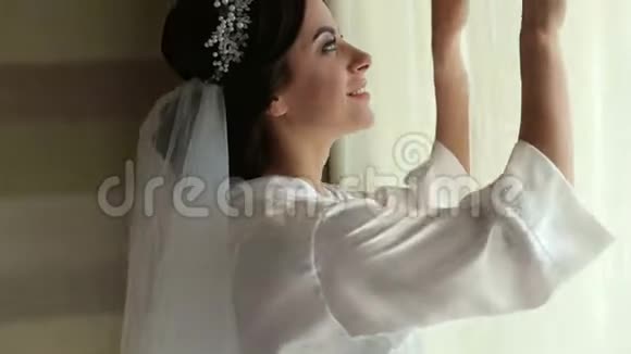 靠近窗户的睡袍中温柔新娘的肖像视频的预览图