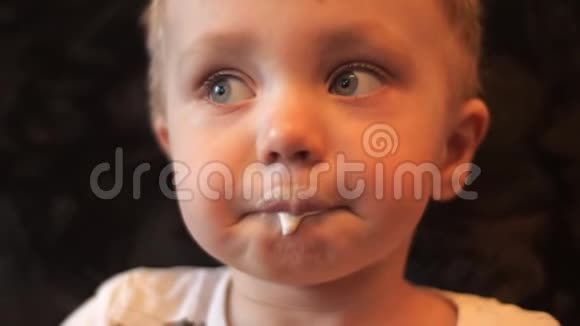 一个小男孩的特写镜头他吃了一个白色香草冰淇淋脸上慢慢地涂抹着它视频的预览图