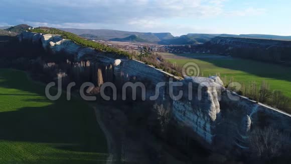 鸟瞰美丽的天然石壁高高的和长长的悬崖两边都生长着树木和绿色的田野视频的预览图