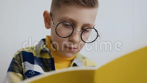 一个戴圆眼镜在笔记本上做笔记的时髦男孩的肖像特写戴眼镜的漂亮男孩视频的预览图