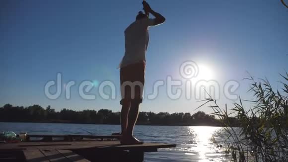 年轻人在湖边的一个木制码头练习瑜伽动作和姿势做伸展运动的运动员视频的预览图