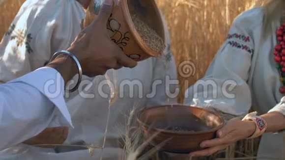 特写镜头动作缓慢印度男人用手把泥锅里的麦粒倒进那个女人的木碗里视频的预览图