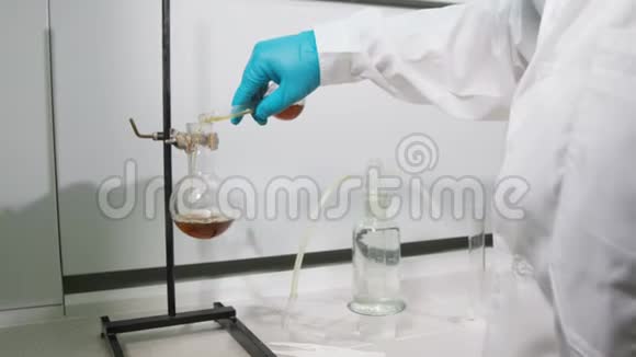 背面视图实验室助理将棕色液体倒入瓶中视频的预览图