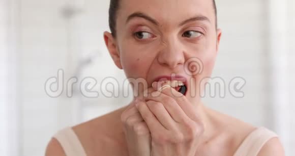 卫生间用牙线清洁牙齿的女人视频的预览图