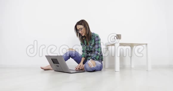 年轻漂亮的女孩坐在家里的地板上用笔记本电脑打视频电话视频的预览图