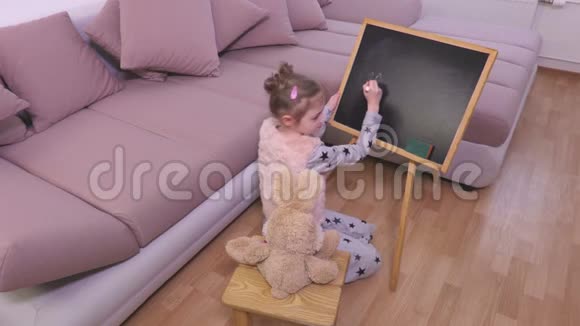 一个小女孩在黑板附近玩兔子玩具视频的预览图