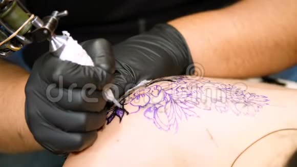 特写在一个纹身沙龙一位专家正在做一个纹身的女人背部黑色油漆花卉装饰一个人工作视频的预览图