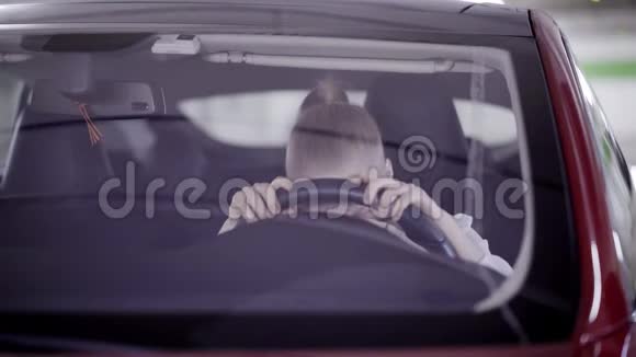 扎着马尾辫的绝望的女士坐在红色的车上把头放在方向盘上视频的预览图