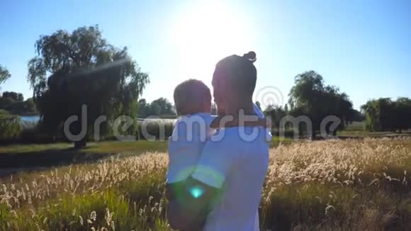年轻的爸爸牵着儿子的手在草地上和他说话一家人在一起的快乐时光视频的预览图