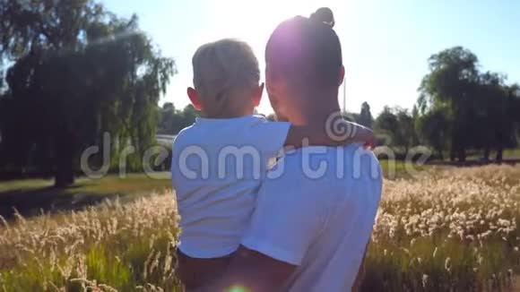 年轻的爸爸在草地上抱着他的孩子小儿子和英俊的父亲指着田野里的东西视频的预览图