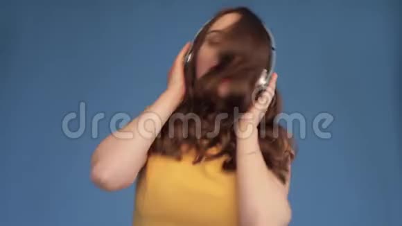 乔维亚年轻的女人一边跳舞一边听耳机里的音乐视频的预览图