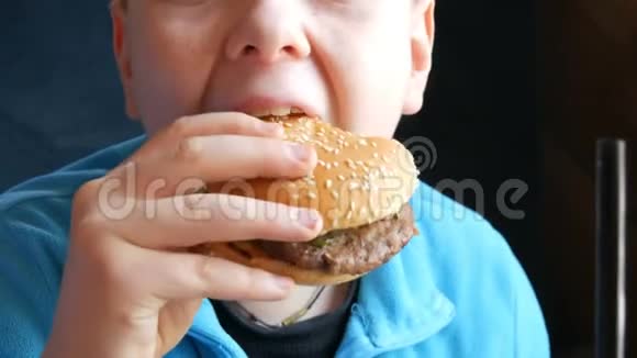 一个蓝眼睛的帅哥少年吃大汉堡特写镜头快餐店不健康食品视频的预览图