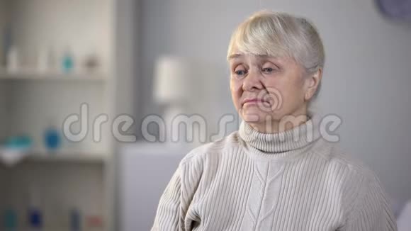 悲伤的老妇人独自坐在客厅里想着健康问题视频的预览图