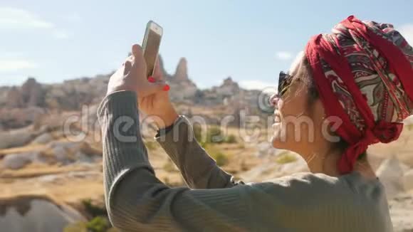 年轻的混合种族旅游女孩在手机上拍摄沙漠全景视频卡帕多西亚土耳其4K视频的预览图