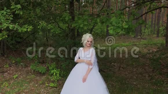 森林里美丽的金发新娘抚摸着自己挺直了头发视频的预览图