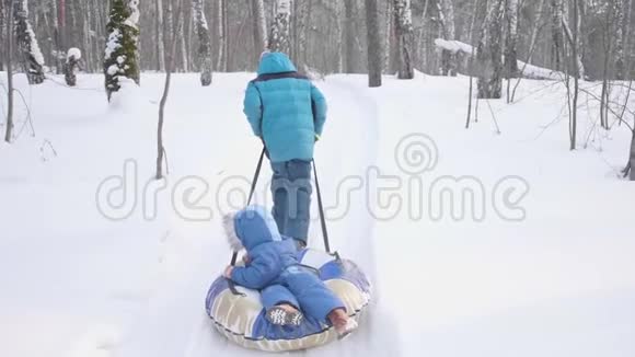 两个孩子在冬季公园散步坐雪橇户外活动和散步视频的预览图