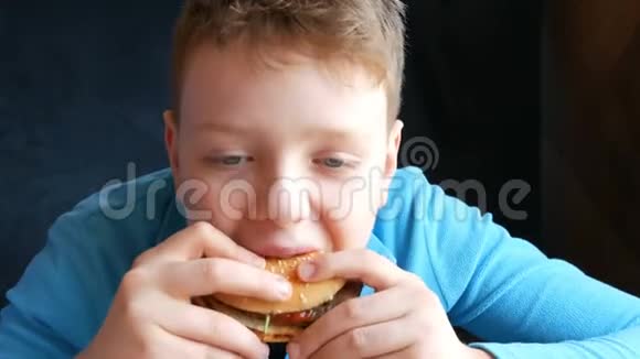 餐厅快餐不是健康食品蓝眼睛帅哥少年吃一个大汉堡视频的预览图