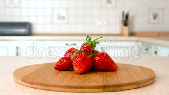 把新鲜的整个草莓收起来旋转相机与白色厨房的背景多利射击视频的预览图