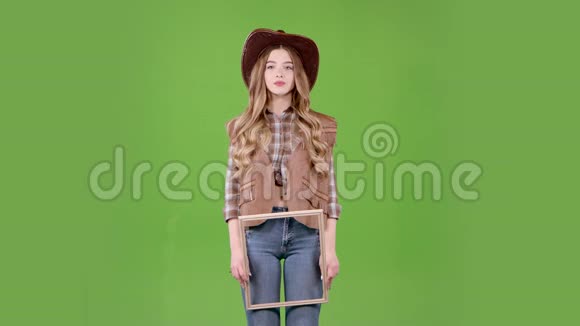 女孩拿着一个木框摆着牛仔的姿势绿色屏幕视频的预览图