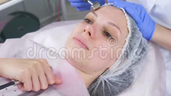 美容师为一个年轻女人做了一个微电流手术面的特写视频的预览图