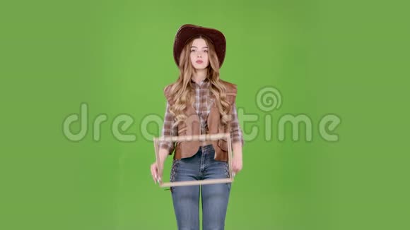 牛仔女孩拿着一个木框摆出一个牛仔的姿势绿色屏幕视频的预览图