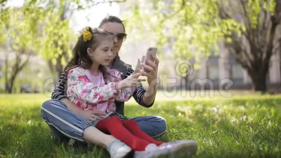 照片自拍家庭母亲和小孩女儿拥抱亲吻照片通过智能手机在散步视频的预览图