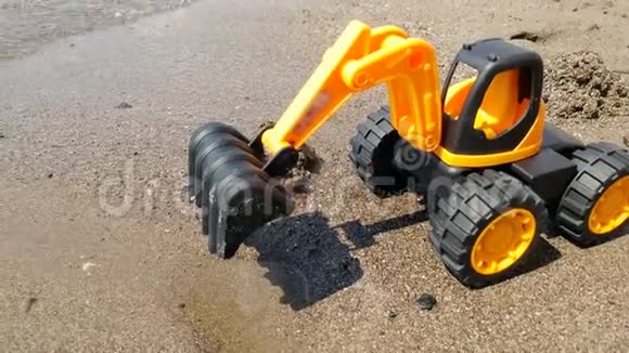 玩具橙色挖掘机站在沙滩上的特写4k视频视频的预览图