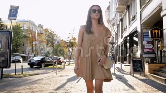 日落时分美丽时尚的女人在街上散步的慢镜头视频的预览图
