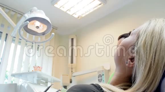 牙科医生调节灯和看病人坐在椅子上的4k特写镜头视频的预览图