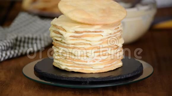 在家里做一层一层的拿破仑蛋糕把奶油蛋糕放在烘焙的糕点上视频的预览图
