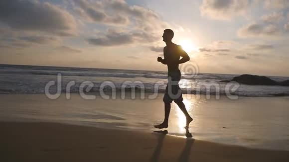 男运动员在户外运动日出时运动员沿着海岸慢跑年轻的运动健将视频的预览图