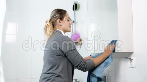 女青年用蓝布清洁浴室镜子4K镜头视频的预览图