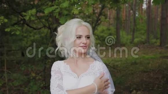 森林里美丽的金发新娘抚摸着自己挺直了头发视频的预览图