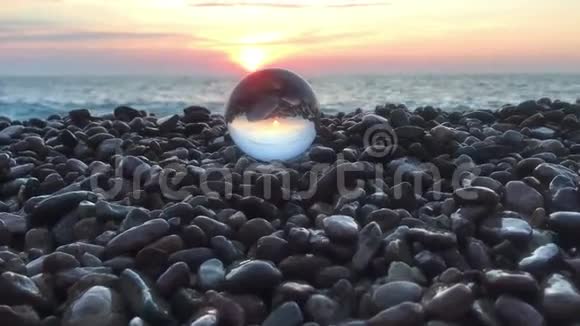 在石头上的水晶球里阳光洒在水面上沙滩上风景中充满了夕阳的倒影视频的预览图