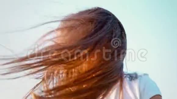一个漂亮的小女孩长着飘逸的长发她的头朝不同的方向扭动女孩在玩她的头发视频的预览图