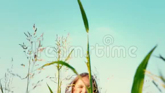 一个留着长长的长发的小女孩跑着一片绿草如茵的田野那孩子伸出双臂去迎接蓝色视频的预览图