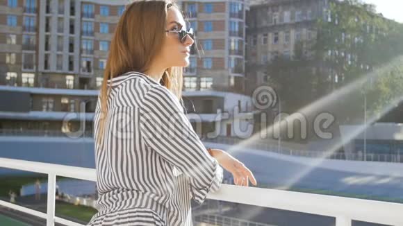 阳光明媚的一天时尚的年轻女士戴着太阳镜站在街上慢动作视频视频的预览图