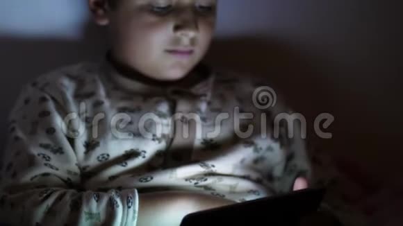 睡觉前男孩在黑暗中玩平板电脑视频的预览图