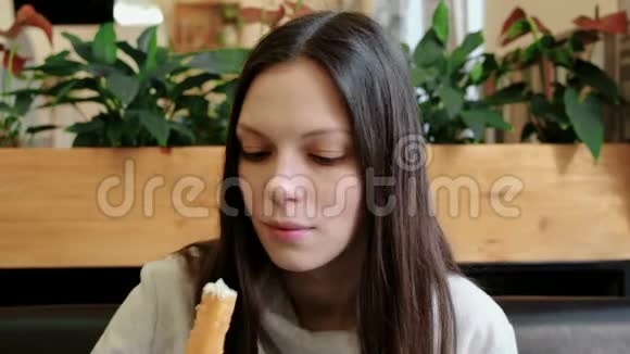 年轻的黑发女人在咖啡馆里吃着新鲜的油炸奶酪棒看着相机微笑着视频的预览图