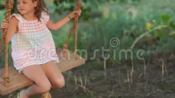 一个女学生正快乐地骑在秋千上暑假快乐棕色眼睛的卷发女孩视频的预览图