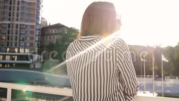 慢动作视频时尚年轻女子站在街上看着城市的日落视频的预览图
