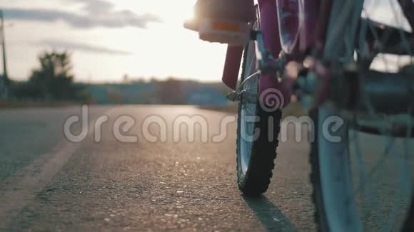 夕阳背景下一个女孩骑自行车的夏日风景剪影孩子在日落时骑自行车视频的预览图
